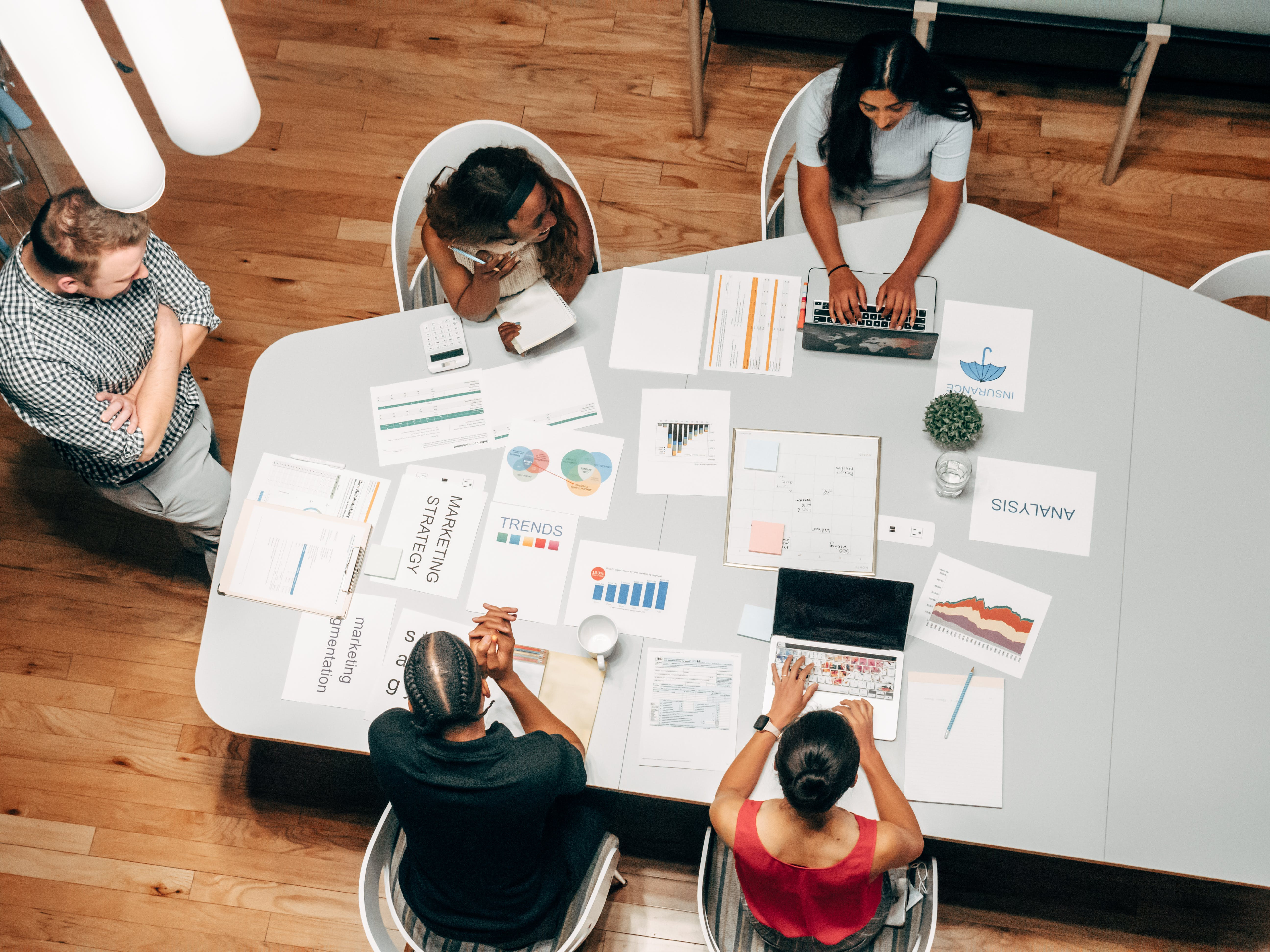 Groep professionals van boven aan een tafel met formulieren en trends